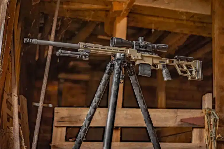 A rifle on top of a tripod in a room.