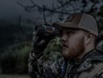 A man in camouflage holding a pair of binoculars.