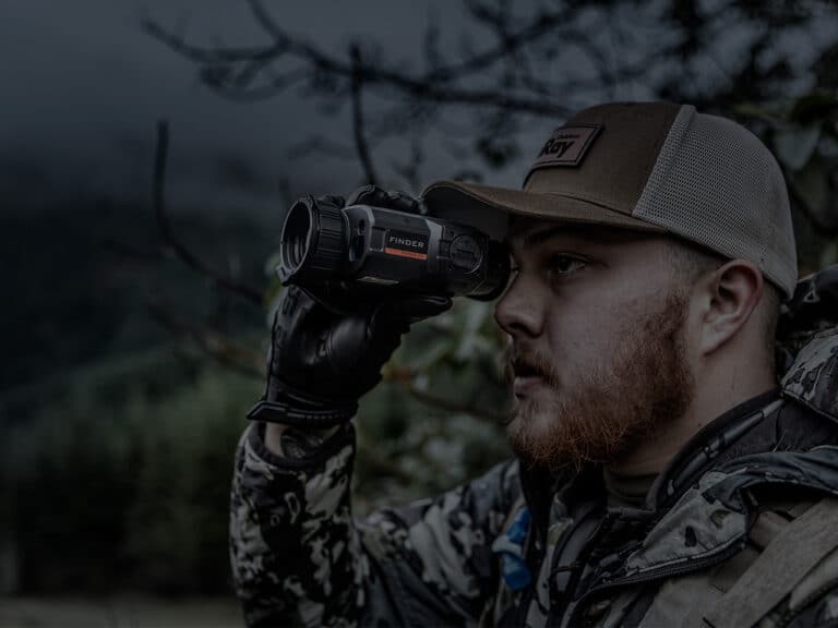 A man in camouflage holding a pair of binoculars.