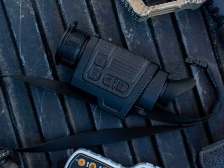 A camera is laying on the ground next to some other items.