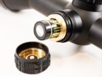 A black and gold camera lens with a white background