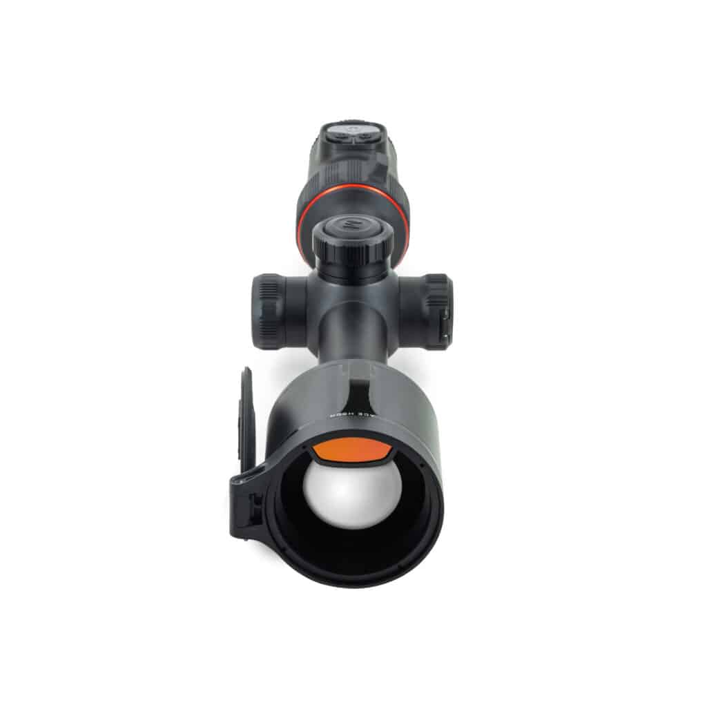A rifle scope with an orange dot in it.