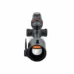A rifle scope with an orange dot in it.