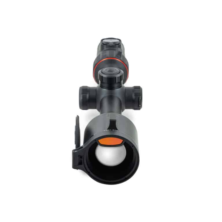 A rifle scope with an orange dot in it.